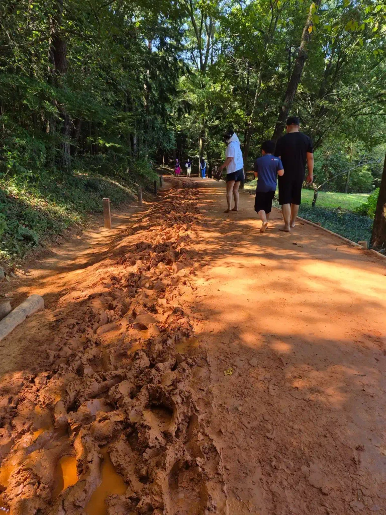 People walking barefoot along the red clay trail at Mulmusan Happy Forest in Korea