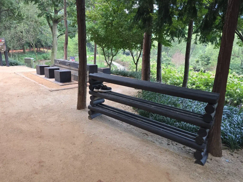Wooden shoe rack beside the barefoot trail at Mulmusan Happy Forest in Yeonggwang
