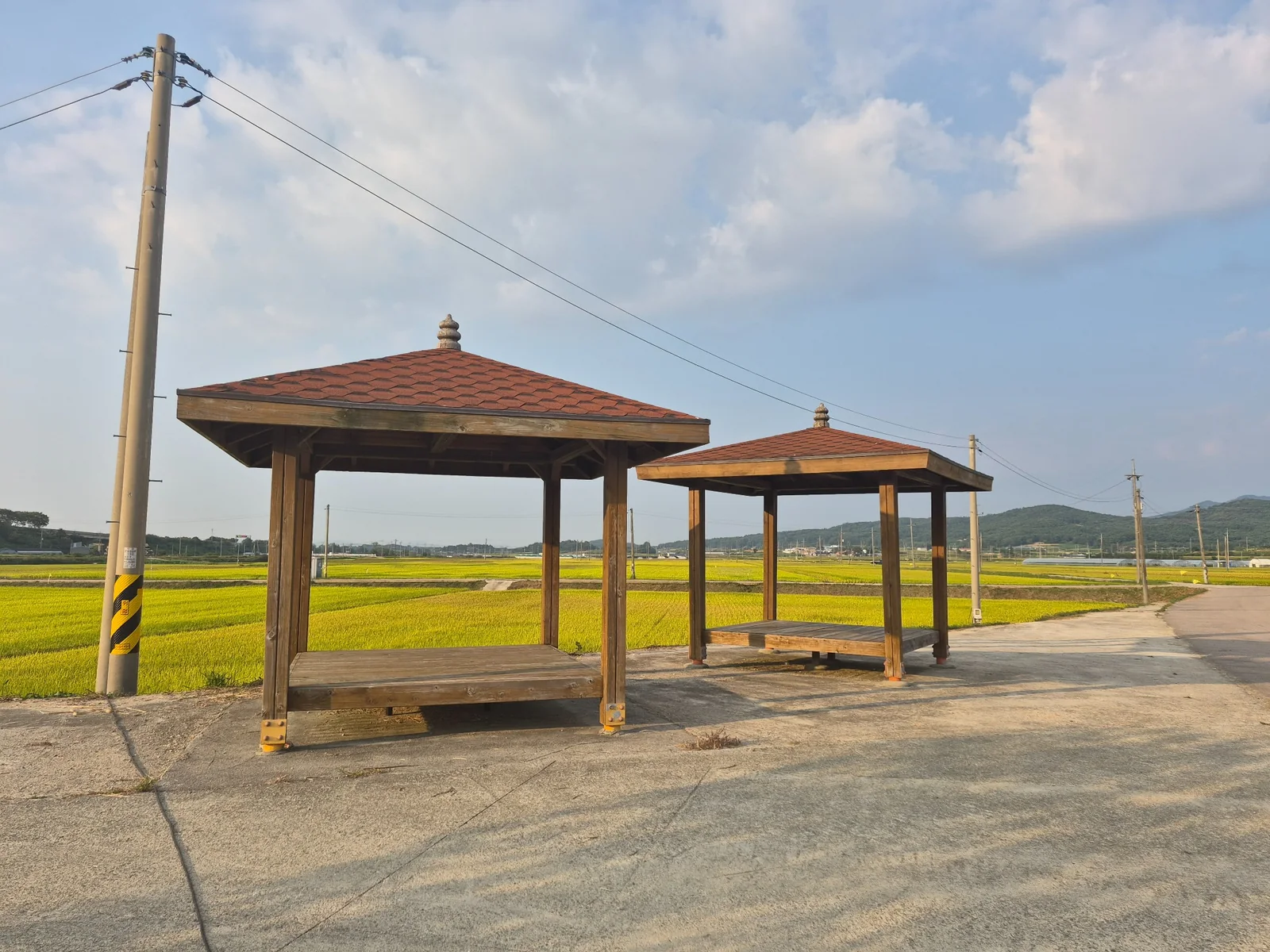 Two wooden rest pavilions beside rice fields in rural South Korea