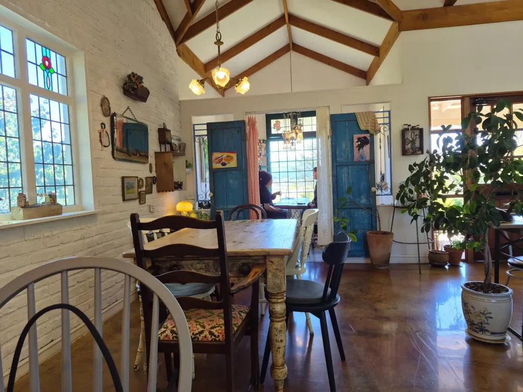 Vintage-style interior of Armeria brunch café with wooden ceiling beams, white brick walls, mismatched chairs and blue wooden doors