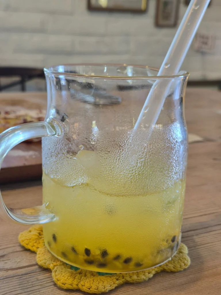 Yellow mango and passion fruit ade with dark passion fruit seeds served in a clear glass mug at Armeria Café in Gochang, South Korea