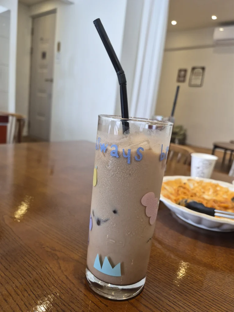 Iced toffee nut latte in a decorated tall glass on a wooden table at Green Eats in Yeonggwang.