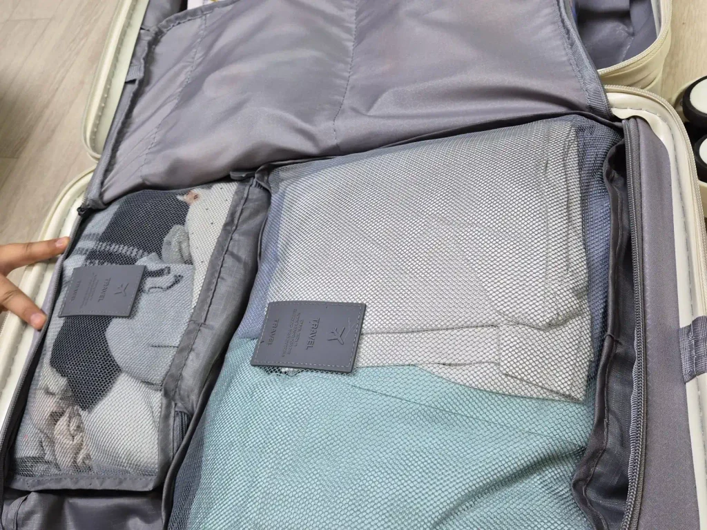 Open suitcase containing clothes and travel essentials packed for a Korean elementary school student's trip to Osaka, Japan